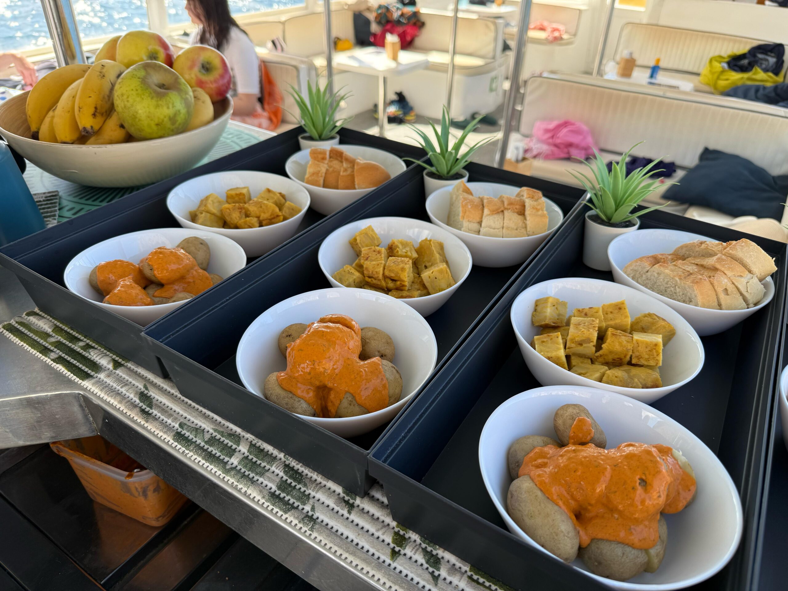 Canarian Food Served on Board – Yellow Boat Mogan Experience Selection of traditional Canarian food including papas arrugadas with mojo, tortilla, and bread, served on board Yellow Boat Mogan during a tasting tour.